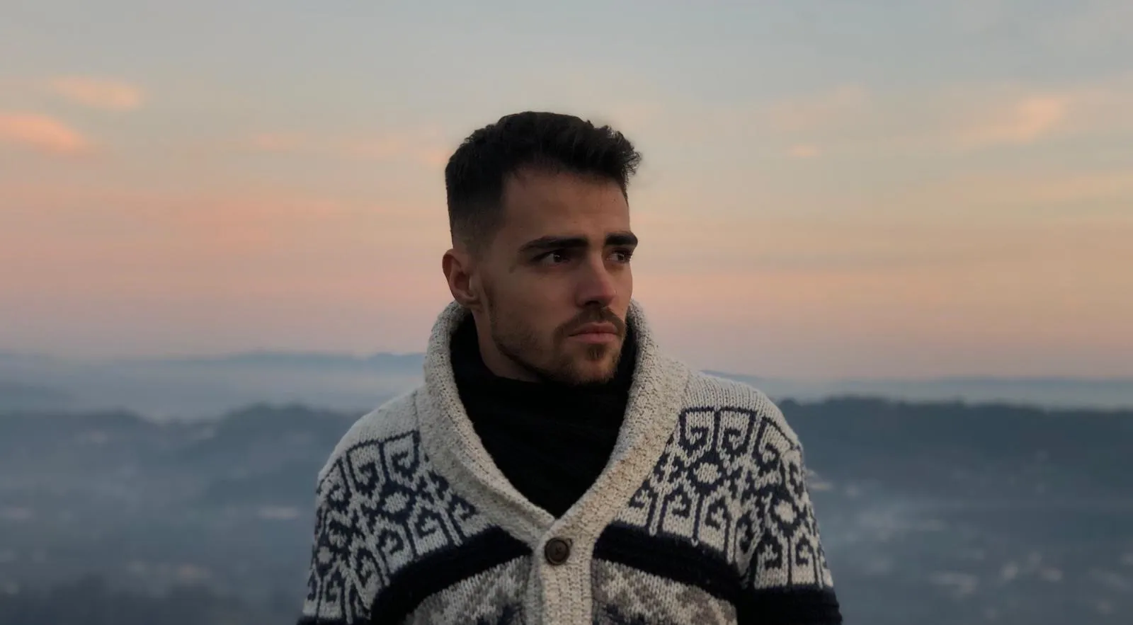 Retrato de Tiago Gil ao ar livre, ao pôr do sol, a olhar para o lado.
